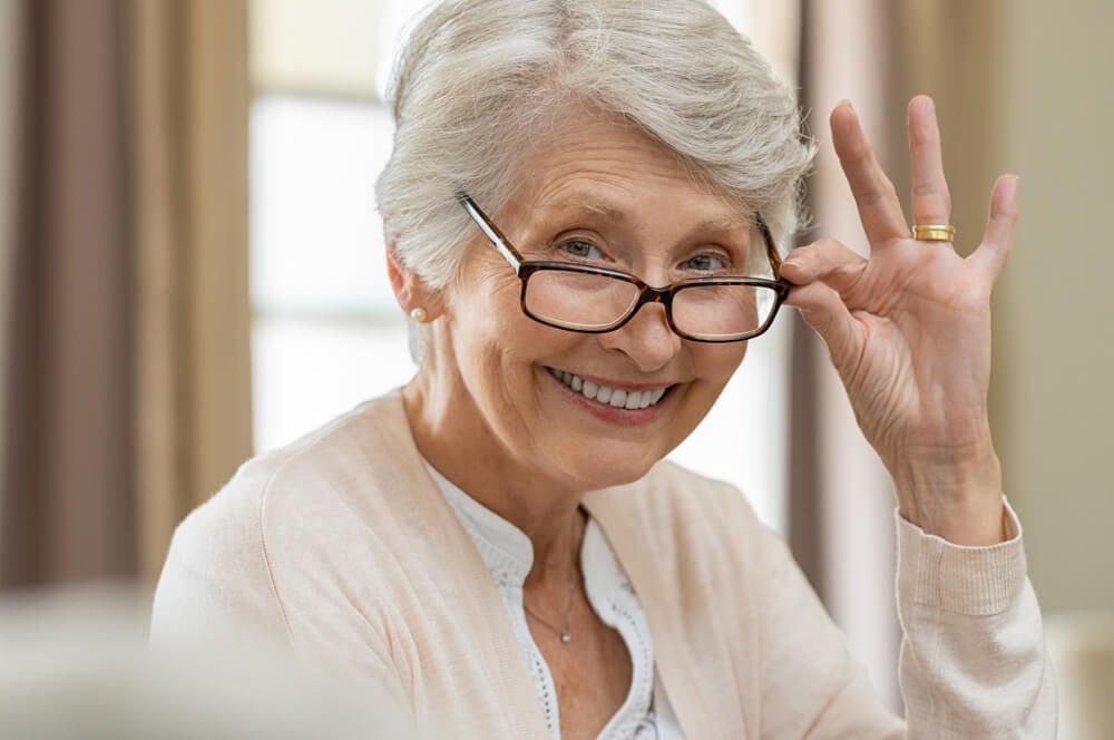 Senior Woman Holding Eyeglasses — Your Ophthalmologist in Townsville, QLD