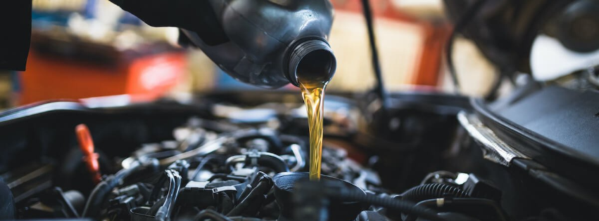 a person is pouring oil into a car engine .