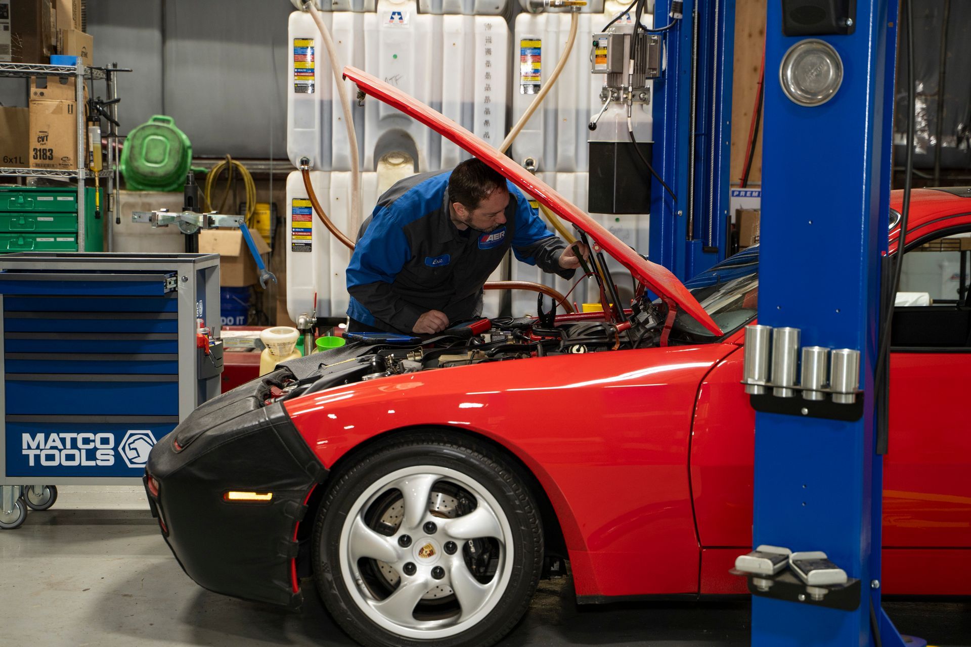 Grove Street Auto Repair Mechanic diagnosing an oil leak on a red sports car