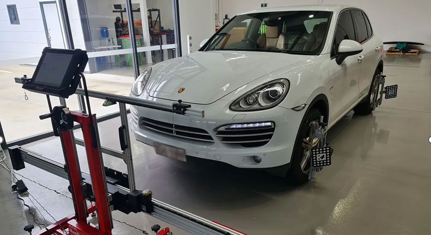 A white porsche cayenne is sitting on a machine in a garage.