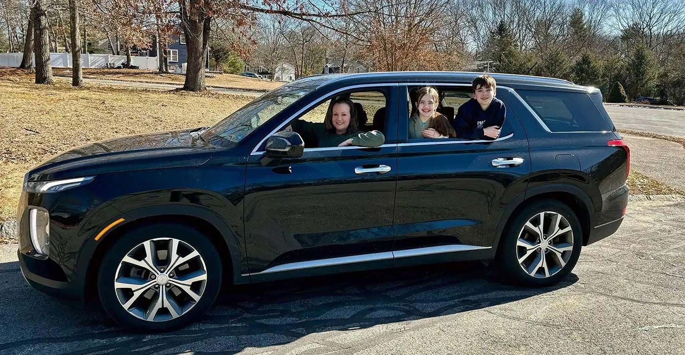 a happy family is sitting in a car and looking out the window