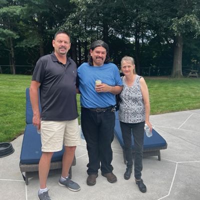 three people are posing for a picture on a patio