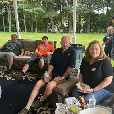 a group of people are sitting on a porch eating food .