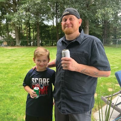 a man and a boy are posing for a picture while the boy is wearing a score shirt .