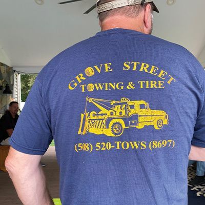 a man wearing a blue shirt that says grove street towing & tire