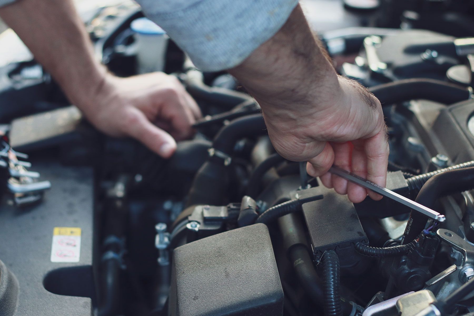Hands using a wrench to work on a car engine.