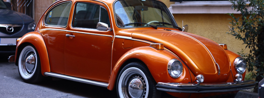 an orange volkswagen beetle is parked on the side of the road