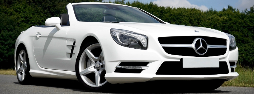 a white mercedes benz slr convertible is parked on the side of the road .
