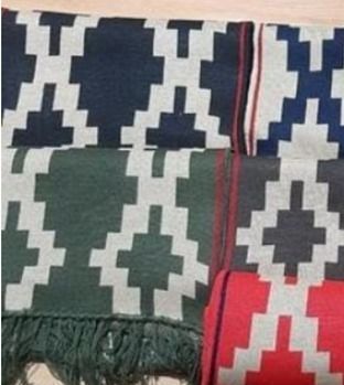 Una manta blanca y negra con flecos reposa sobre una superficie de madera.