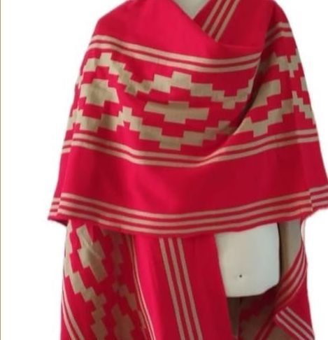 Una manta morada y blanca con un patrón geométrico reposa sobre una superficie de madera.