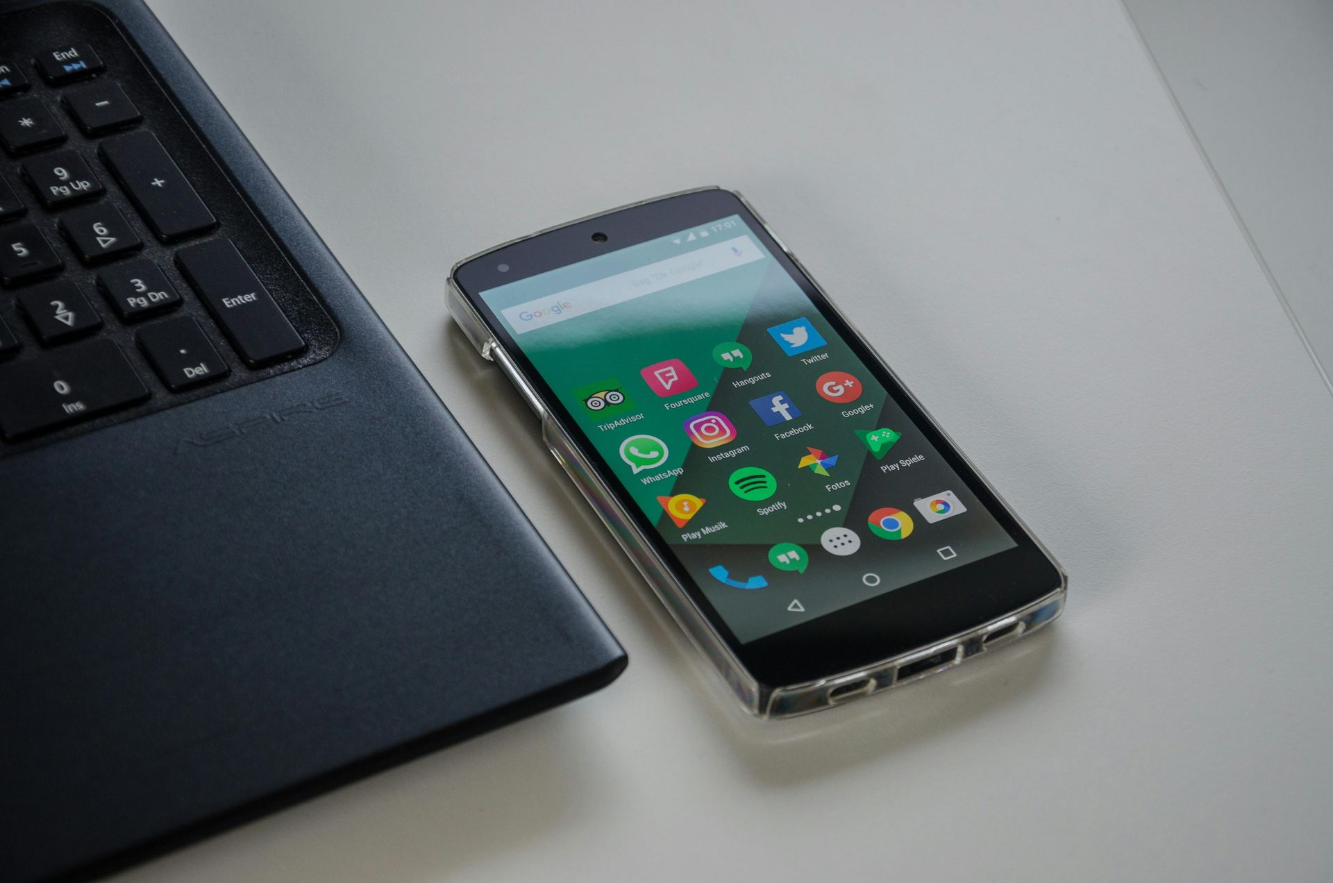 A cell phone is sitting next to a laptop on a table.