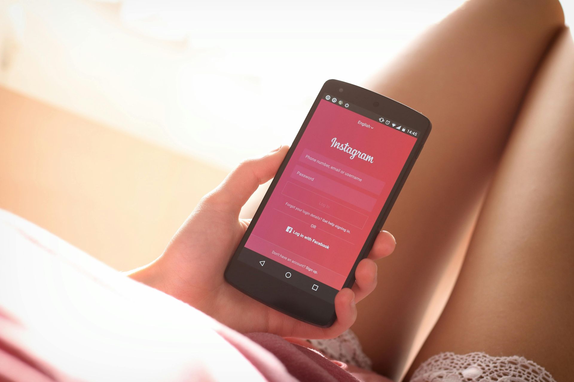 A woman is holding a cell phone with instagram on the screen.
