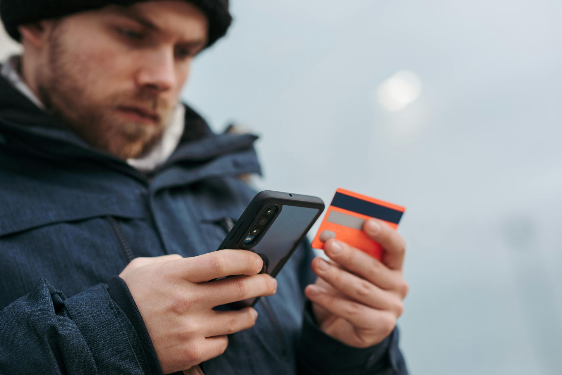 A man is holding a credit card and a cell phone.