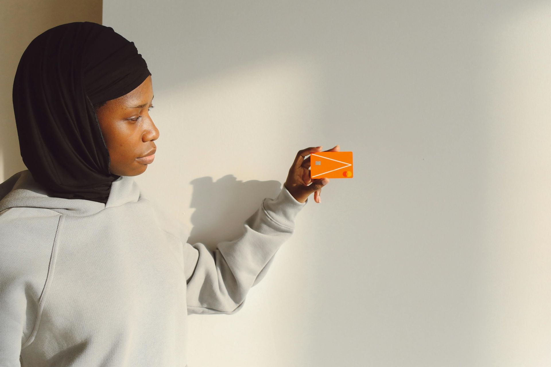 A woman in a hijab is holding a credit card in her hand.
