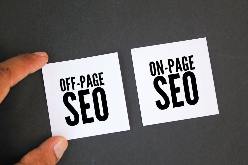 A person is holding two cards that say off page seo and on page seo