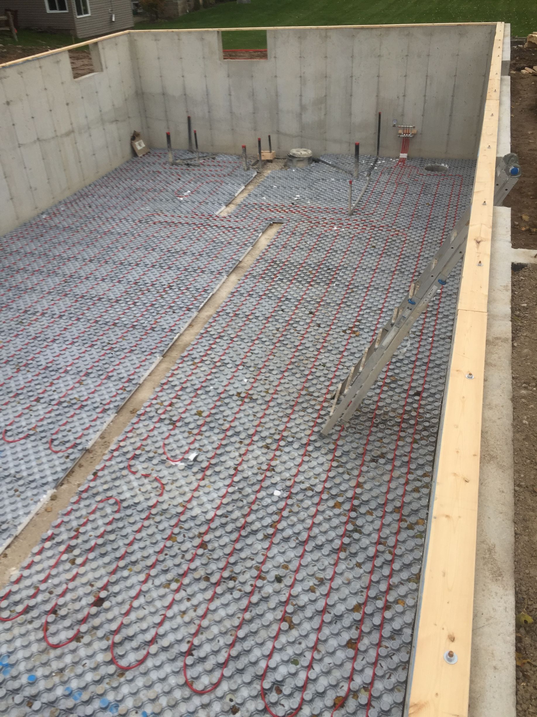 Concrete foundation with red tubing for radiant floor heating installed, ready for concrete pour.