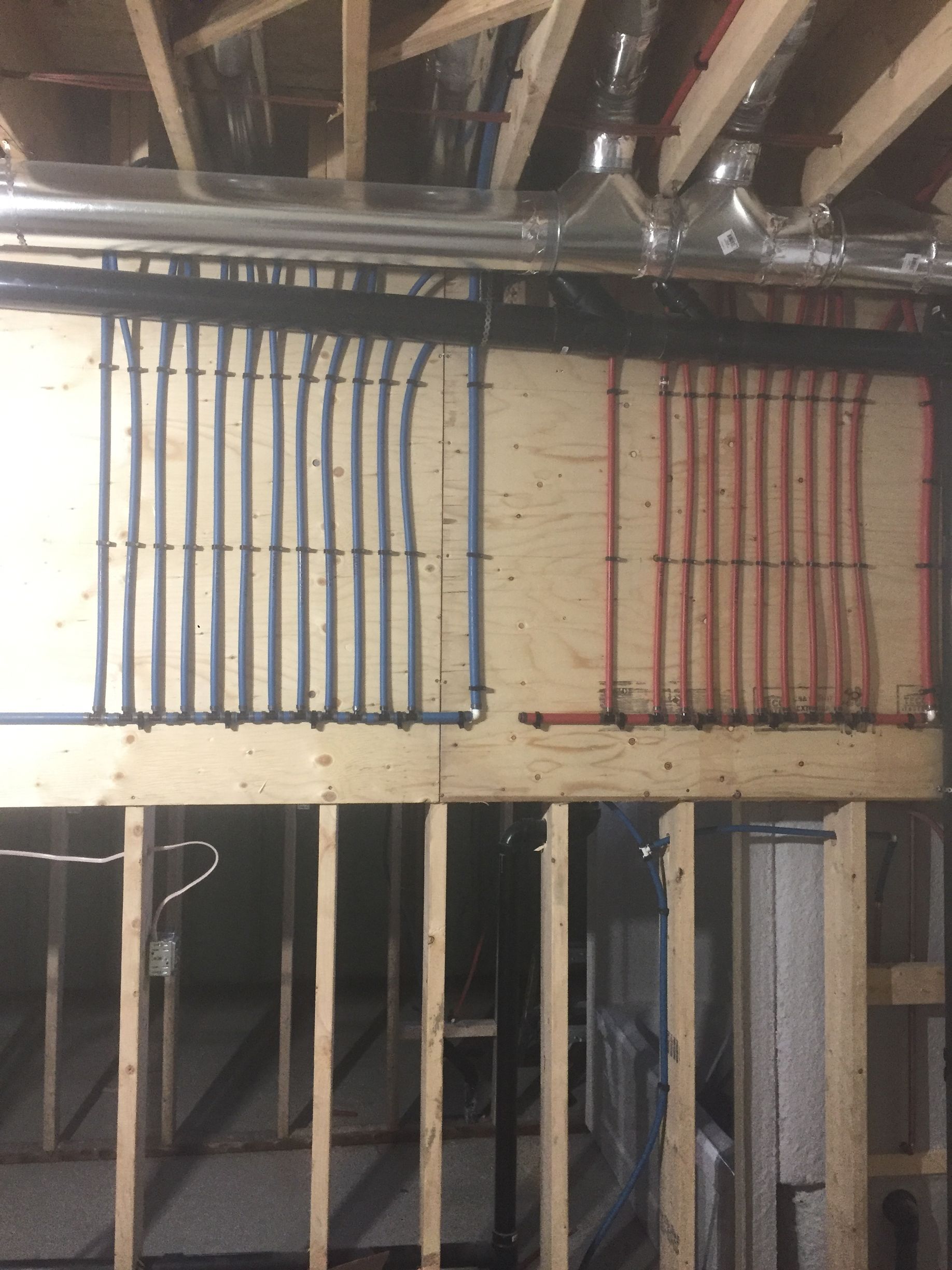 Pipes, blue and red, vertically aligned on a wooden wall in a construction setting.