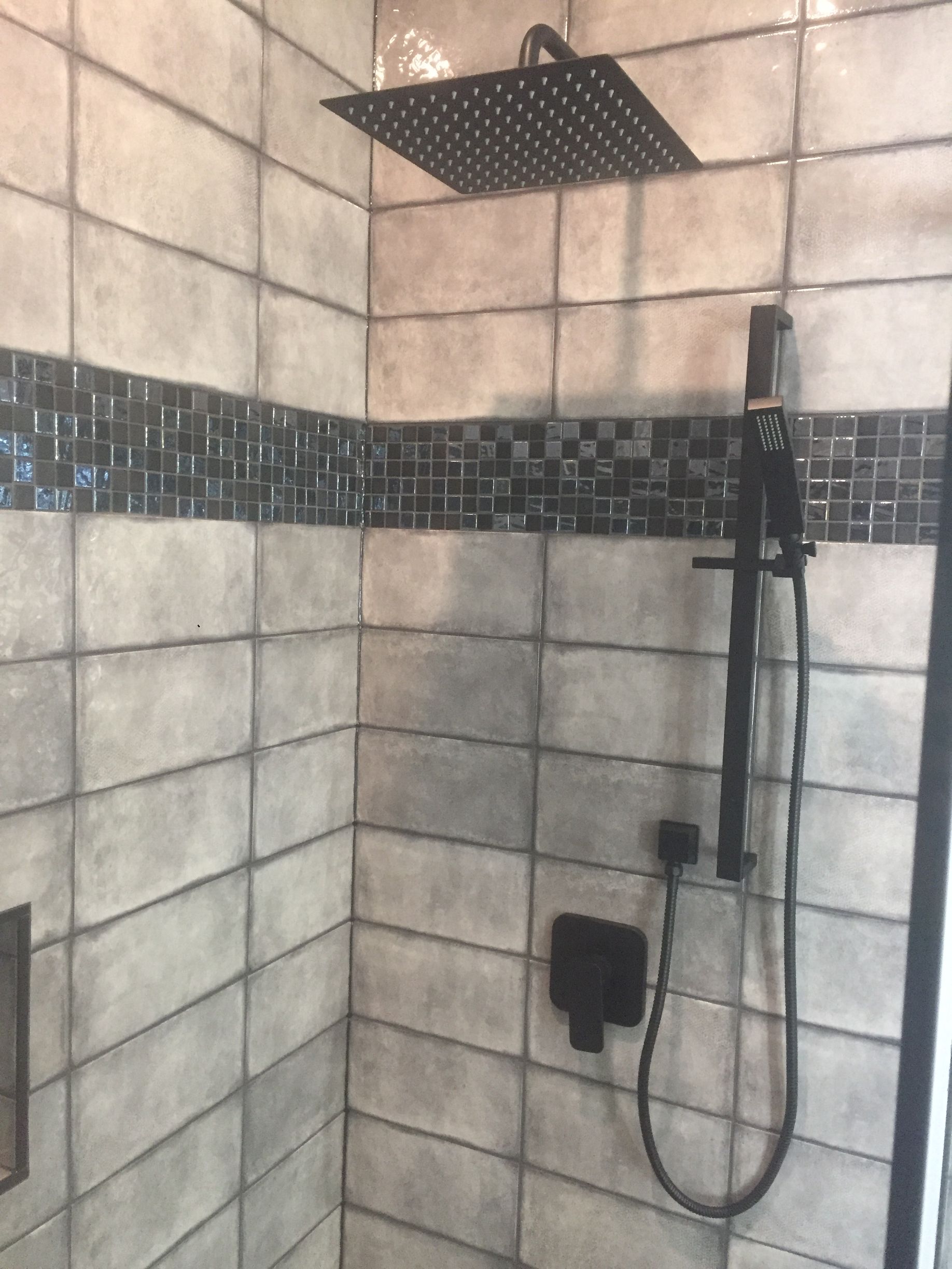Black showerhead and fixtures in a tiled shower.