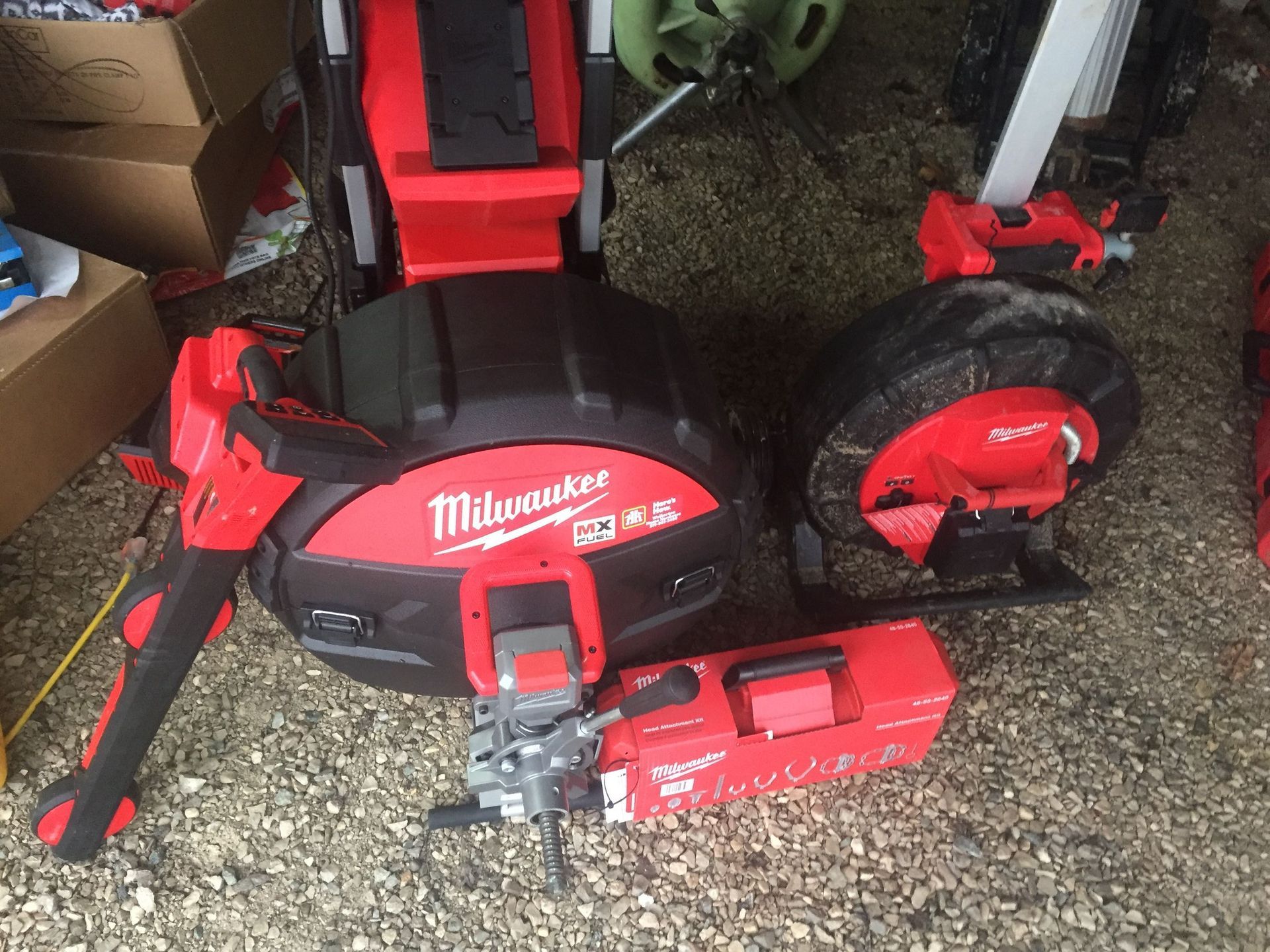 Milwaukee plumbing tools: red and black drain cleaner, pipe cutter, and camera.