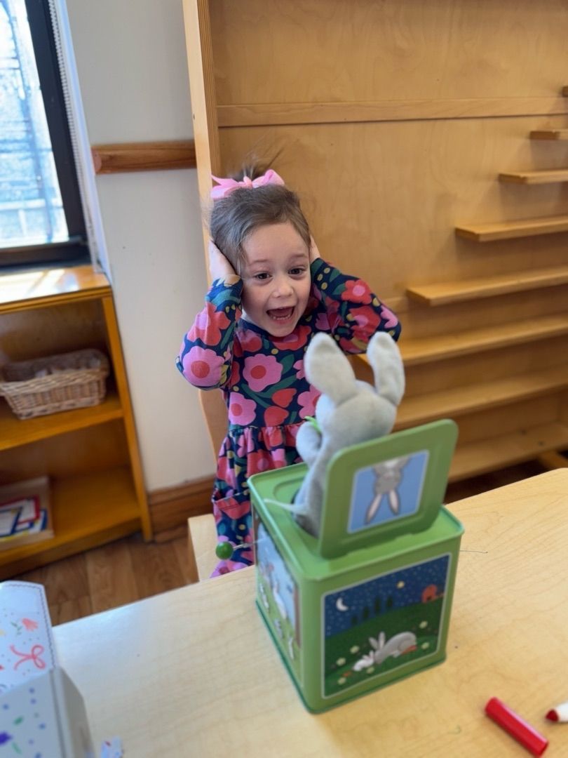Smiling child in colorful clothes behind a green toy block with a white rabbit on top