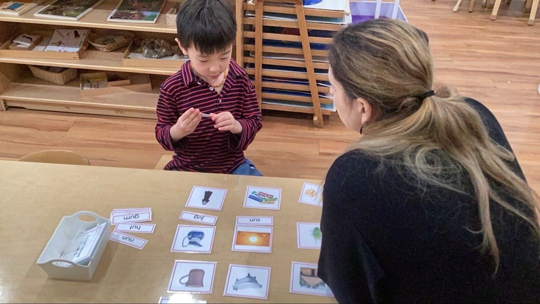 Adult and child at a table matching cards in a classroom setting