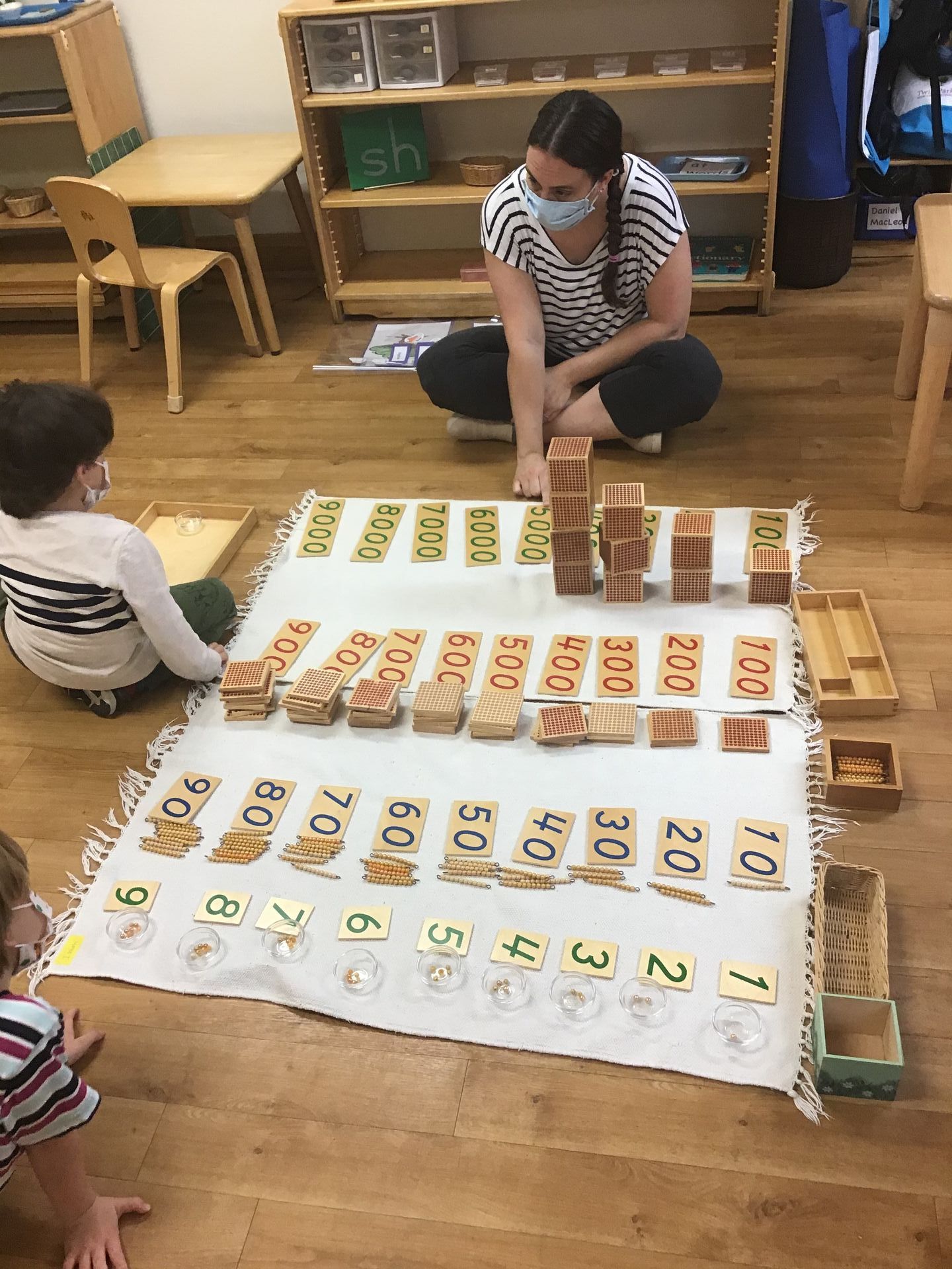 Montessori teacher and students working with Math materials