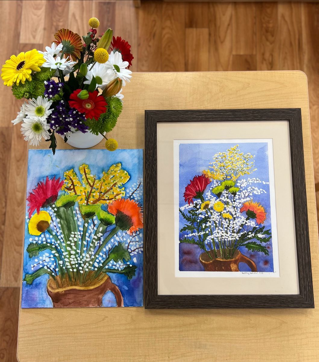 Still life: flower bouquet and paintings on a wooden table.
