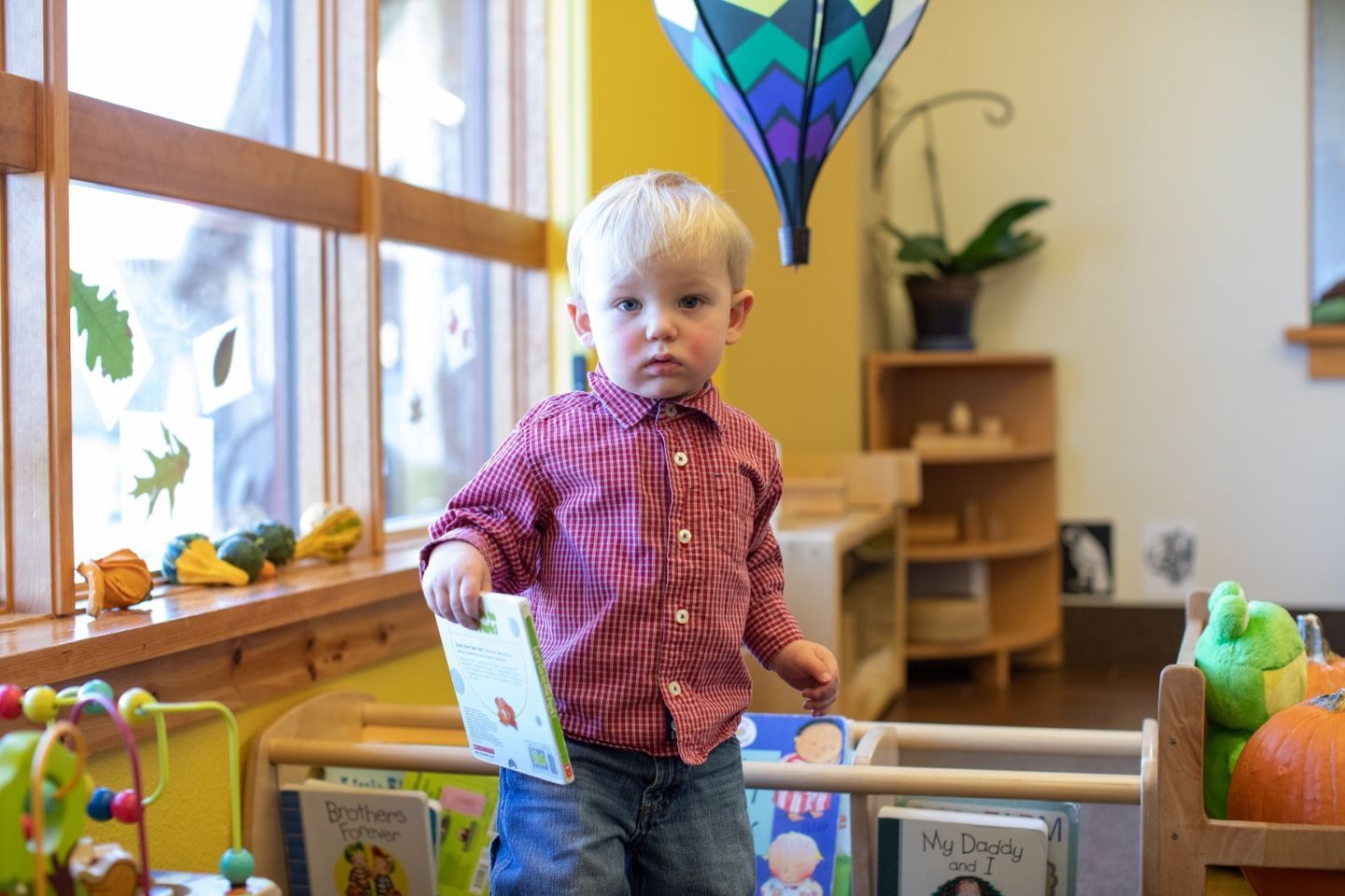 Montessori child reading a book in cozy space, building focus, imagination, and love of stories.