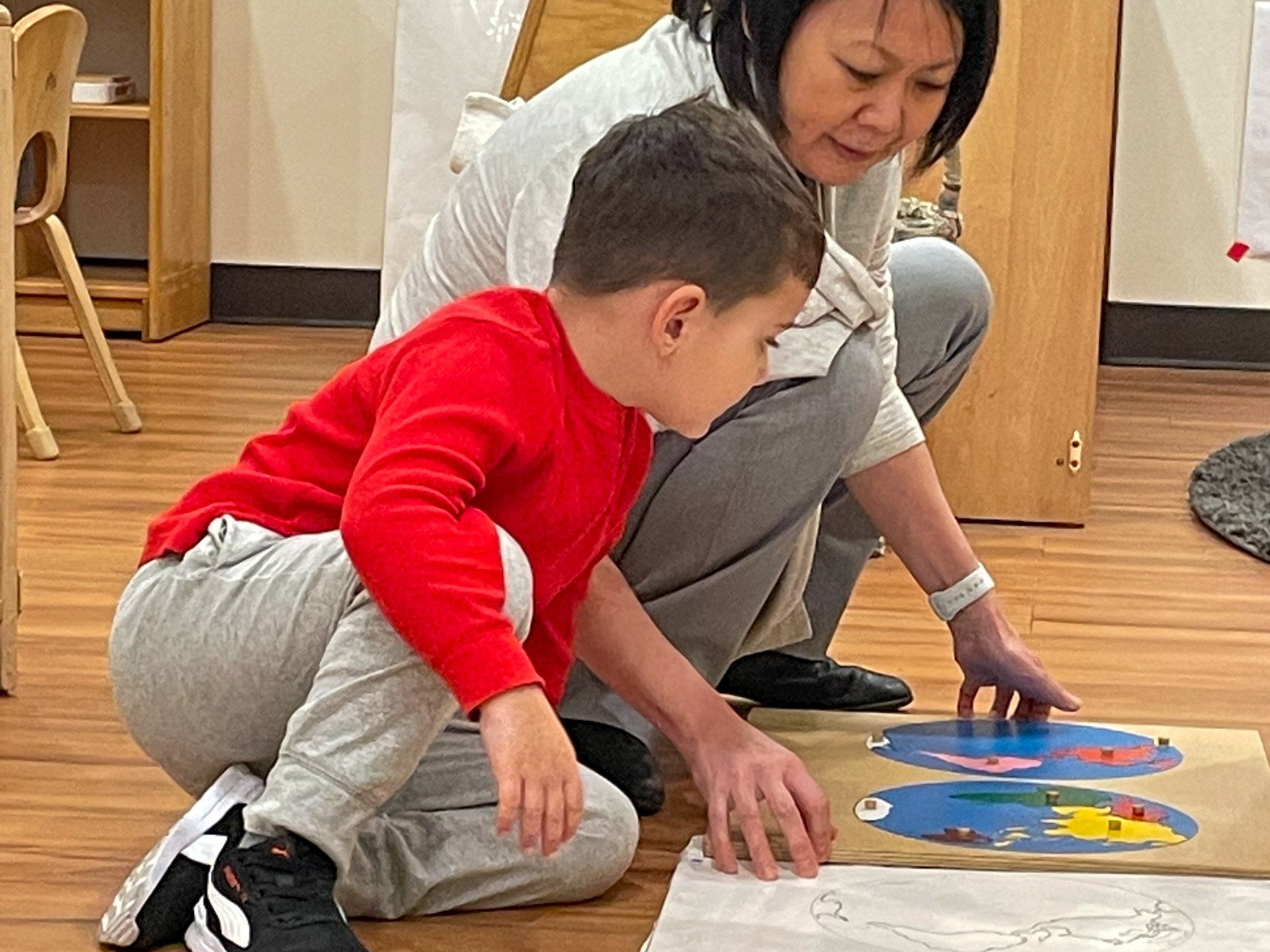 Montessori guide and child working with geography materials