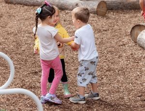 Montessori children playing together outside, learning empathy, cooperation, and friendship skills.
