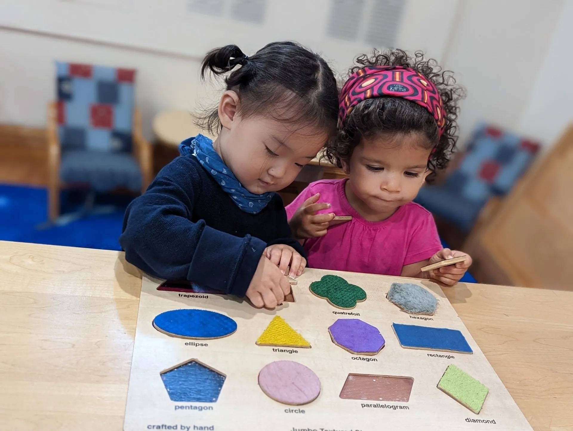 Two young children playing with a shape puzzle at a table; focus on completing the puzzle.