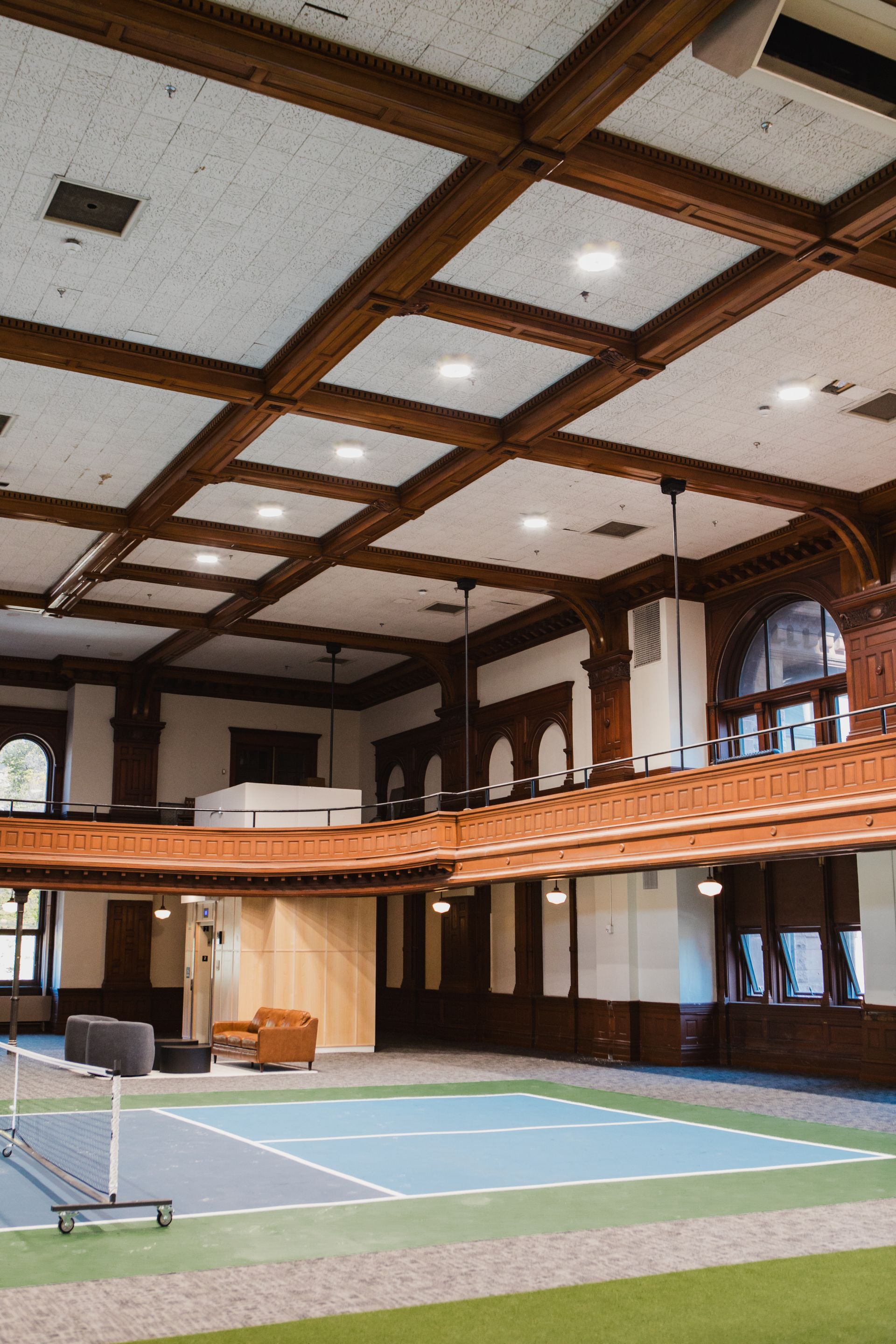 Indoor sports court with wood paneled walls, a balcony, and a coffered ceiling.