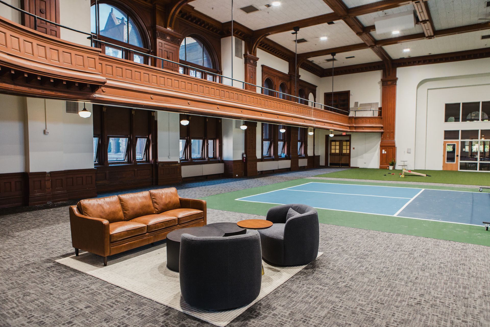 Indoor lounge area with couches, chairs, and a small playing field. Wood and brick architecture, neutral colors.