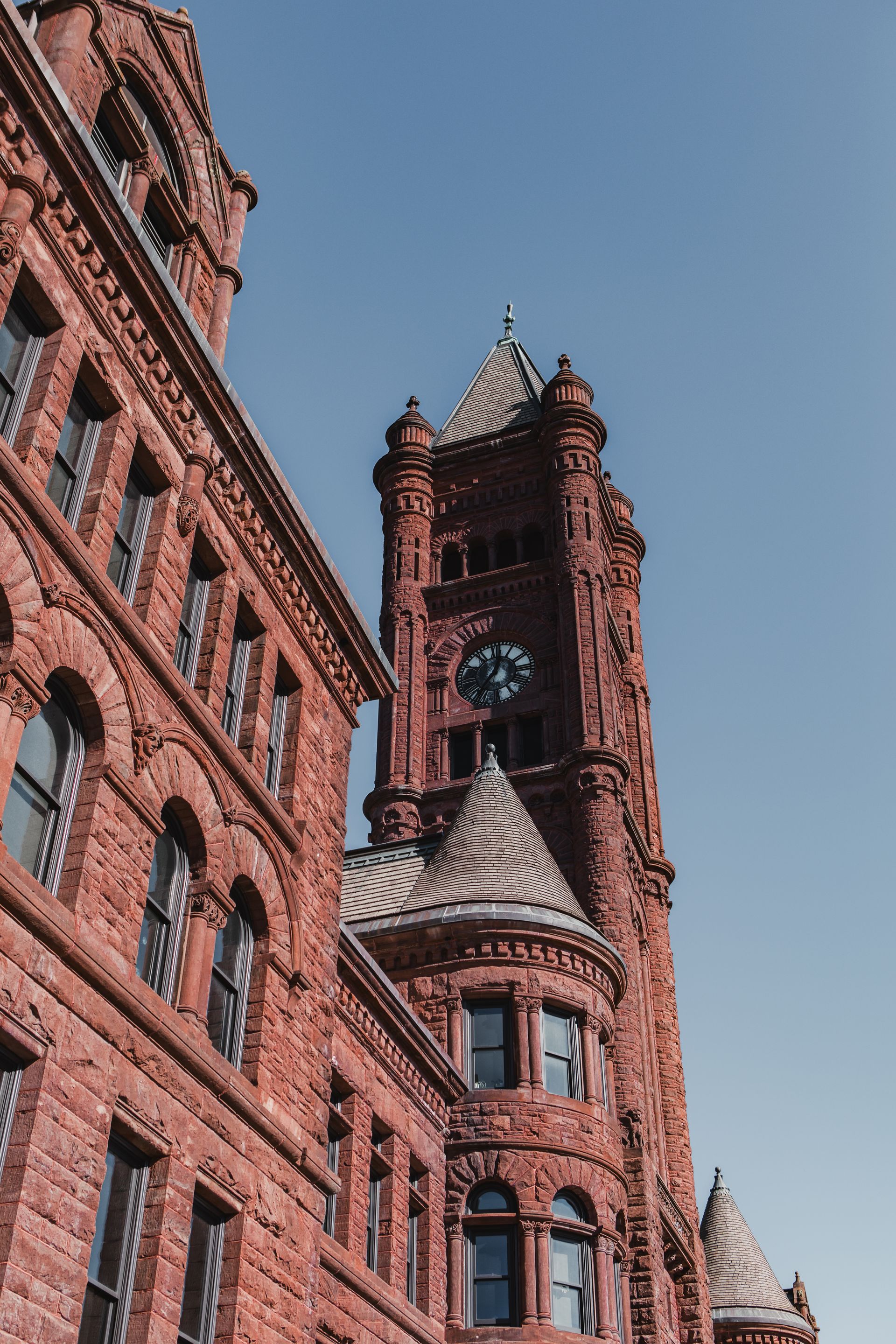 Red brick building with a clock tower against a clear blue sky.