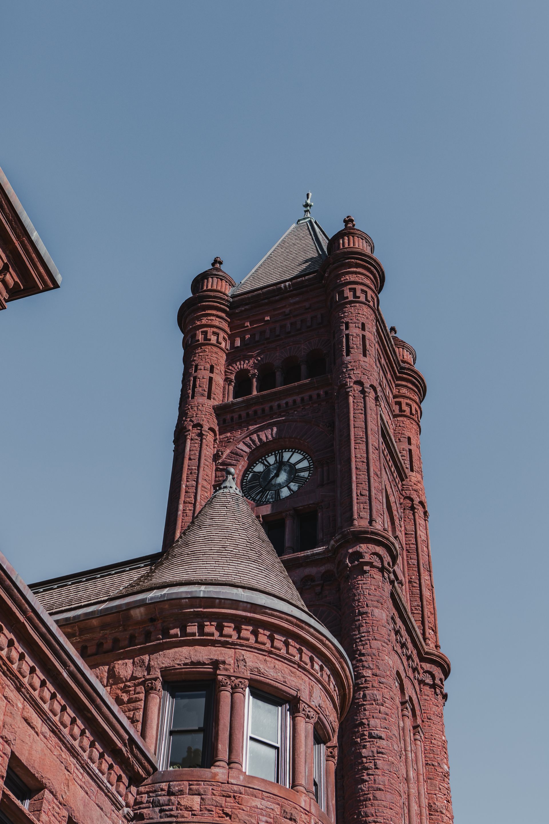 Red brick clock tower against a clear blue sky.