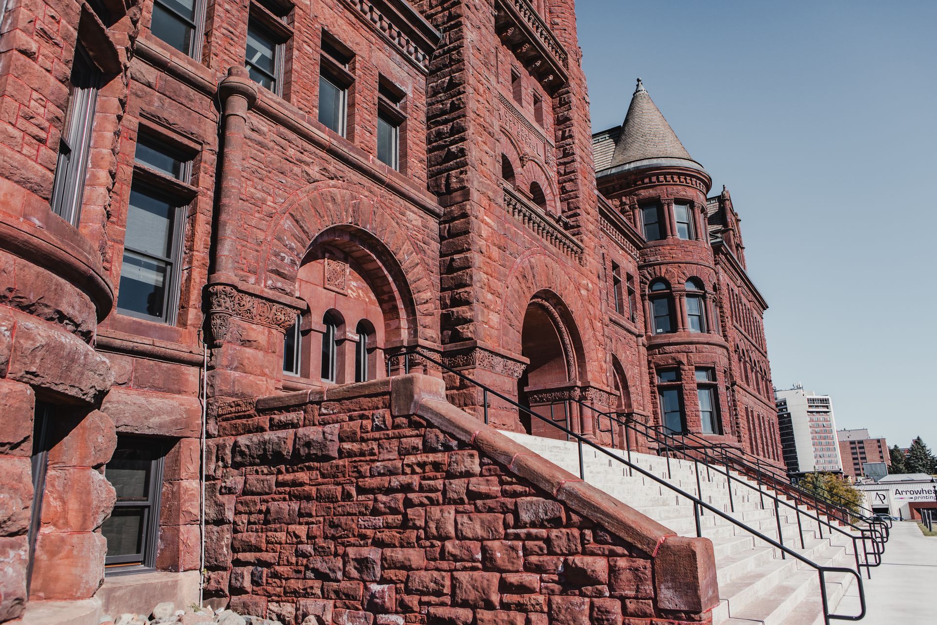 Red brick building with arched windows and steps leading up to the entrance.