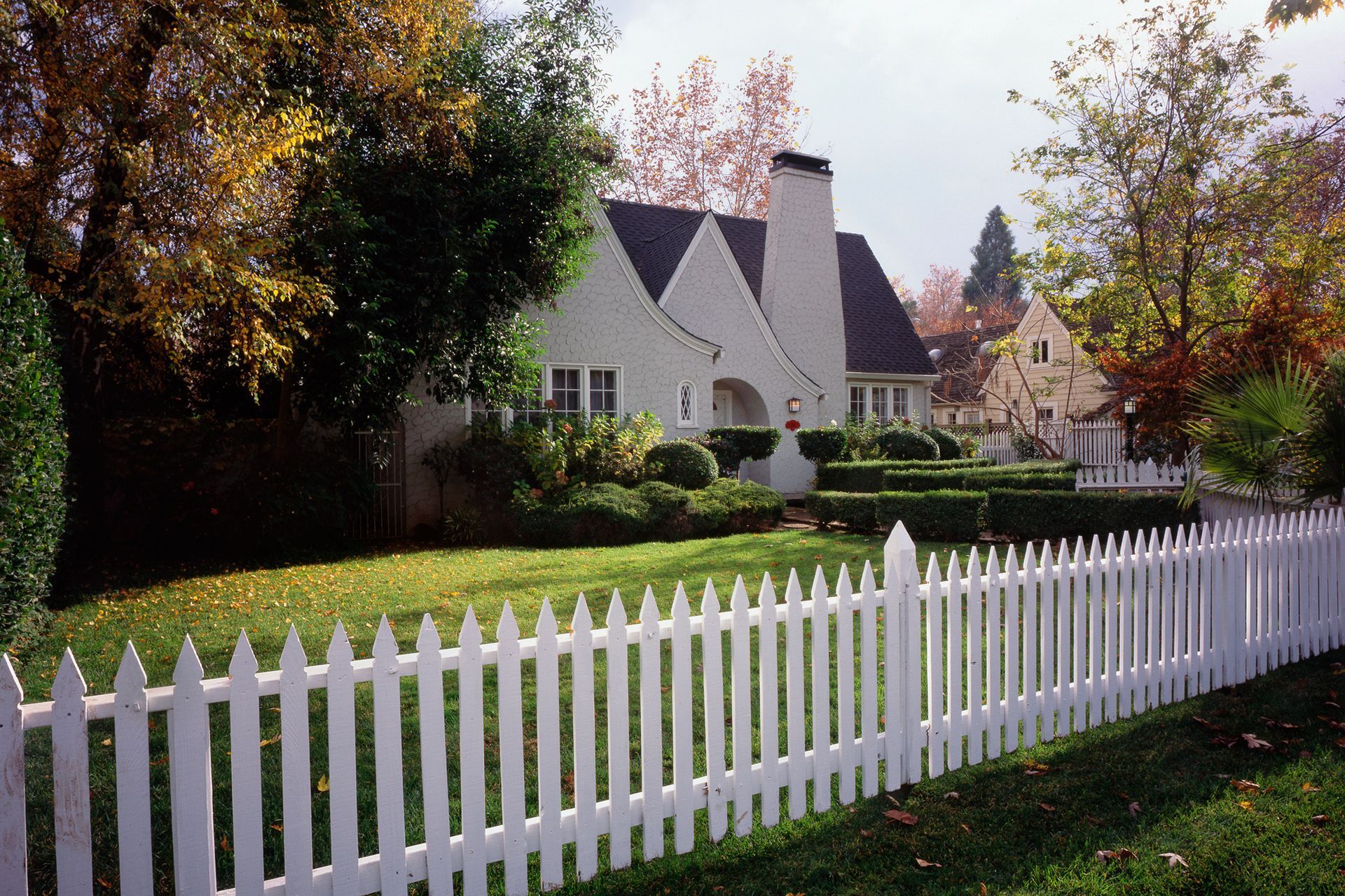 A white picket fence surrounds a white house