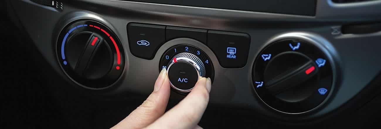 Hand operating A/C control on vehicle dashboard