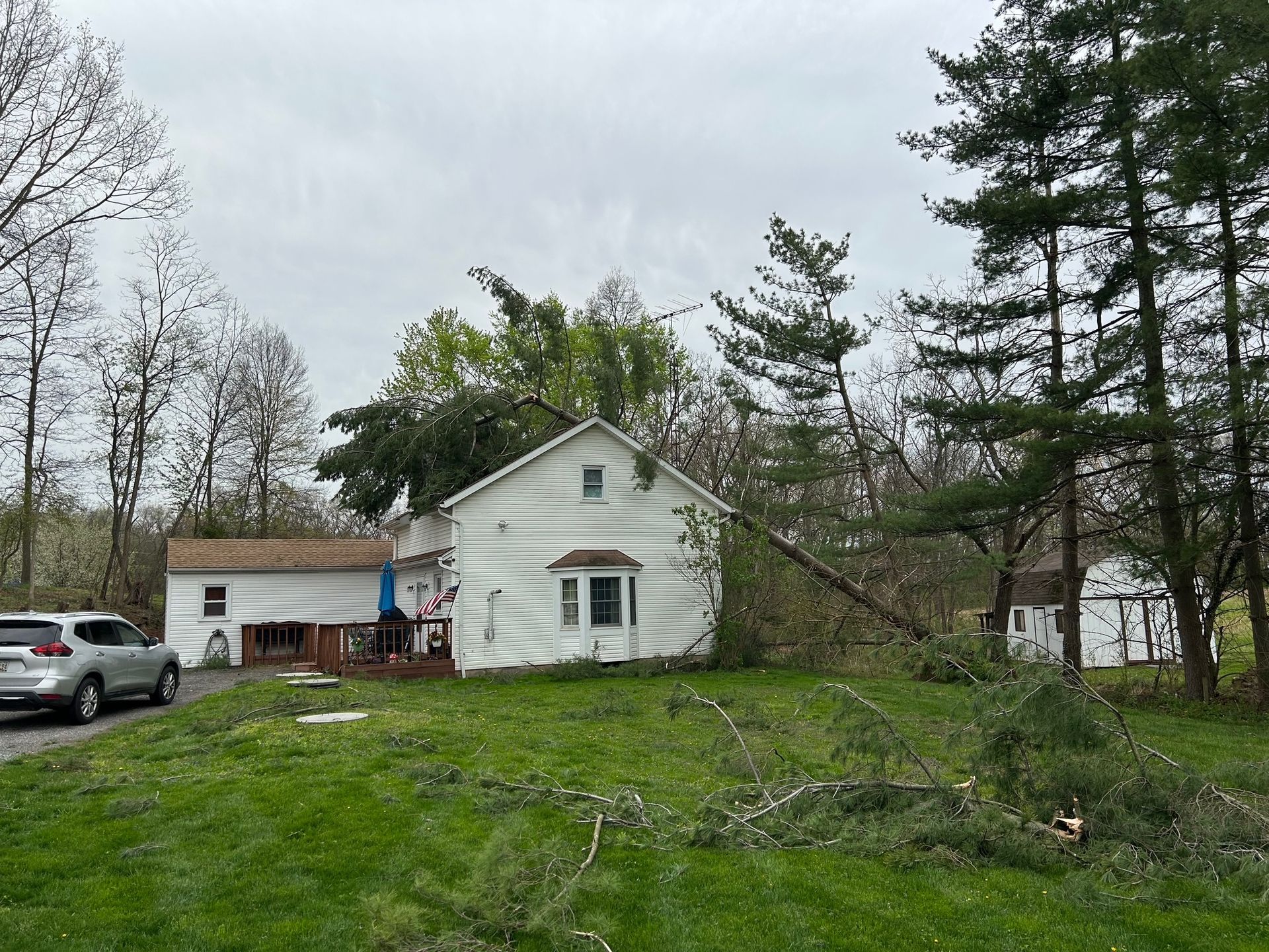 A white house is sitting in the middle of a lush green field surrounded by trees.