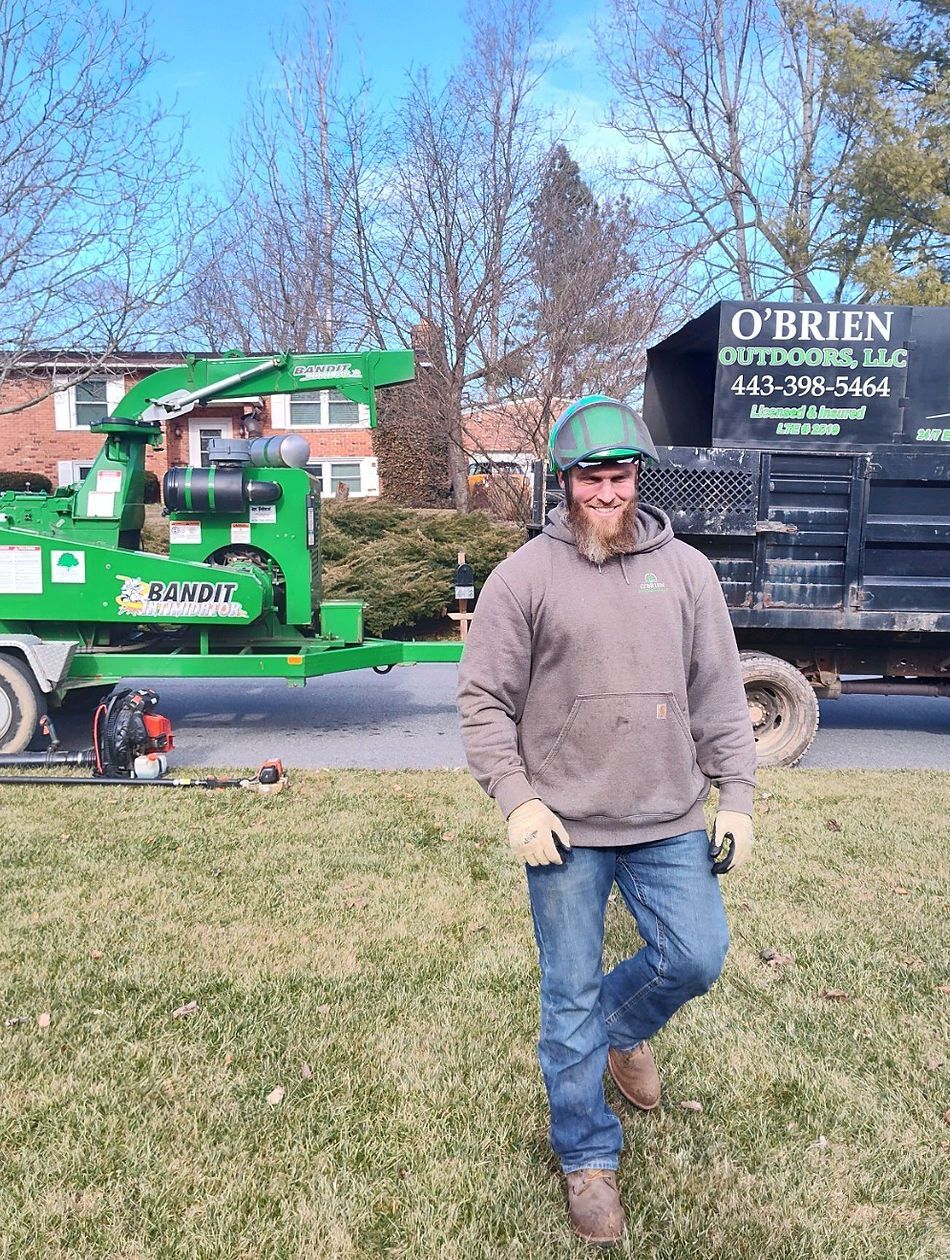 A man is standing in the grass in front of a truck.