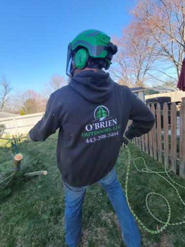A man wearing a helmet and headphones is standing in a yard.