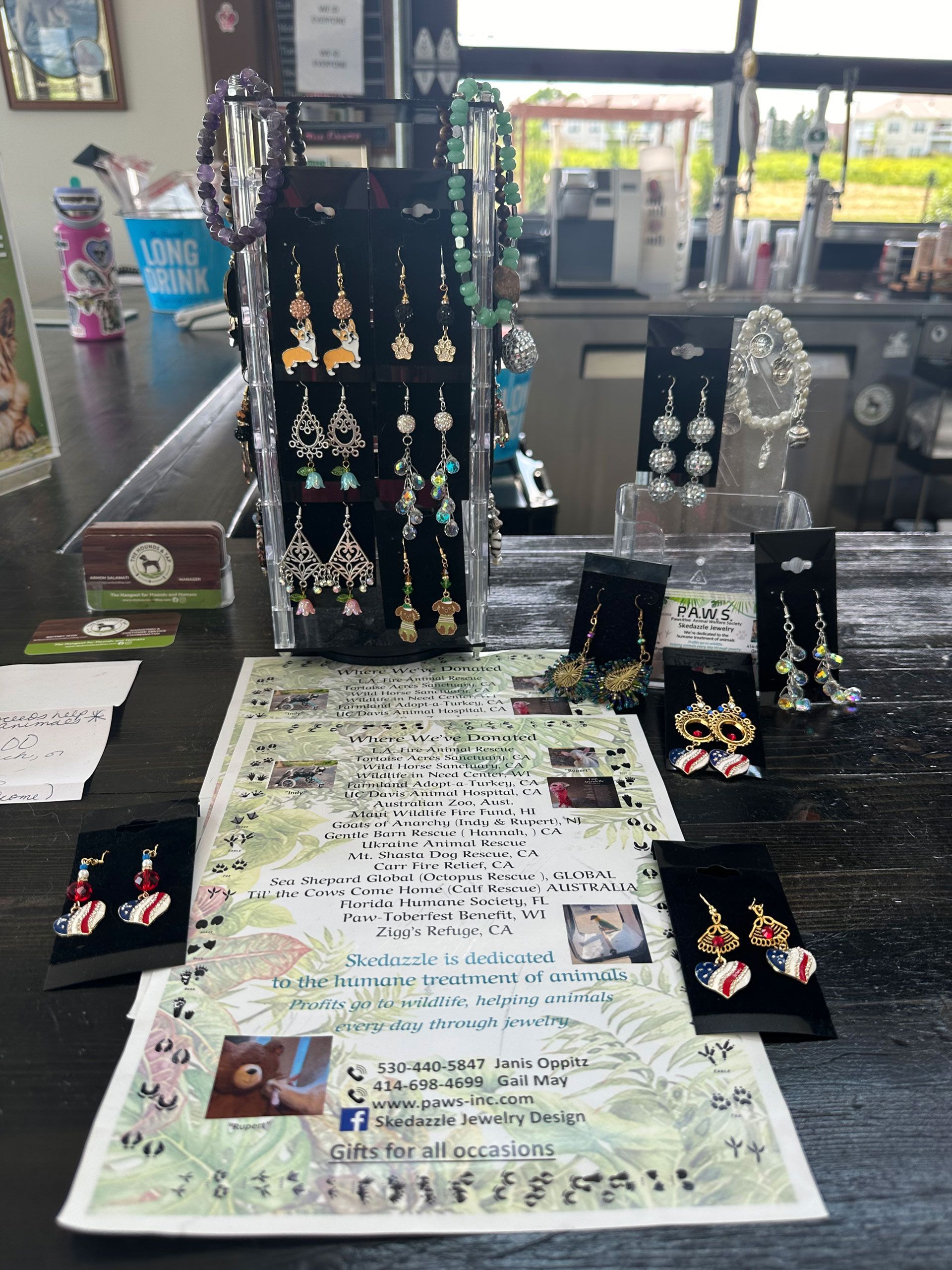 Earrings displayed on a counter in a shop, including pairs on cards and a display stand with various styles.