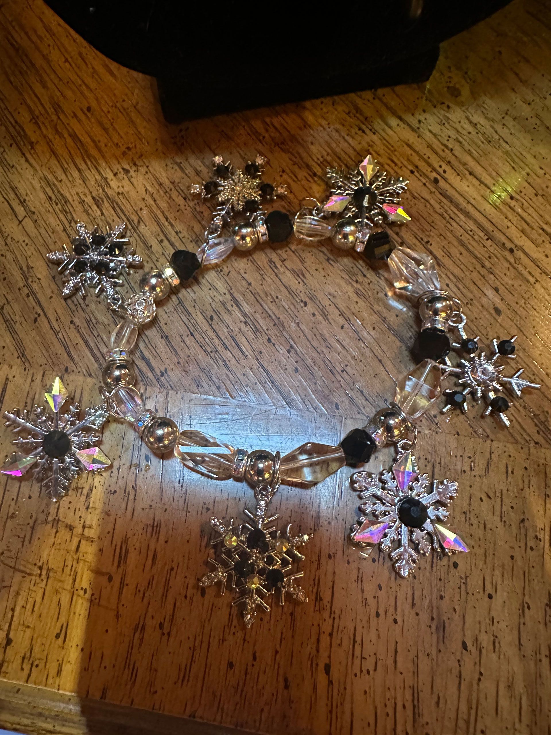 Silver snowflake charm bracelet with iridescent crystals and black beads.