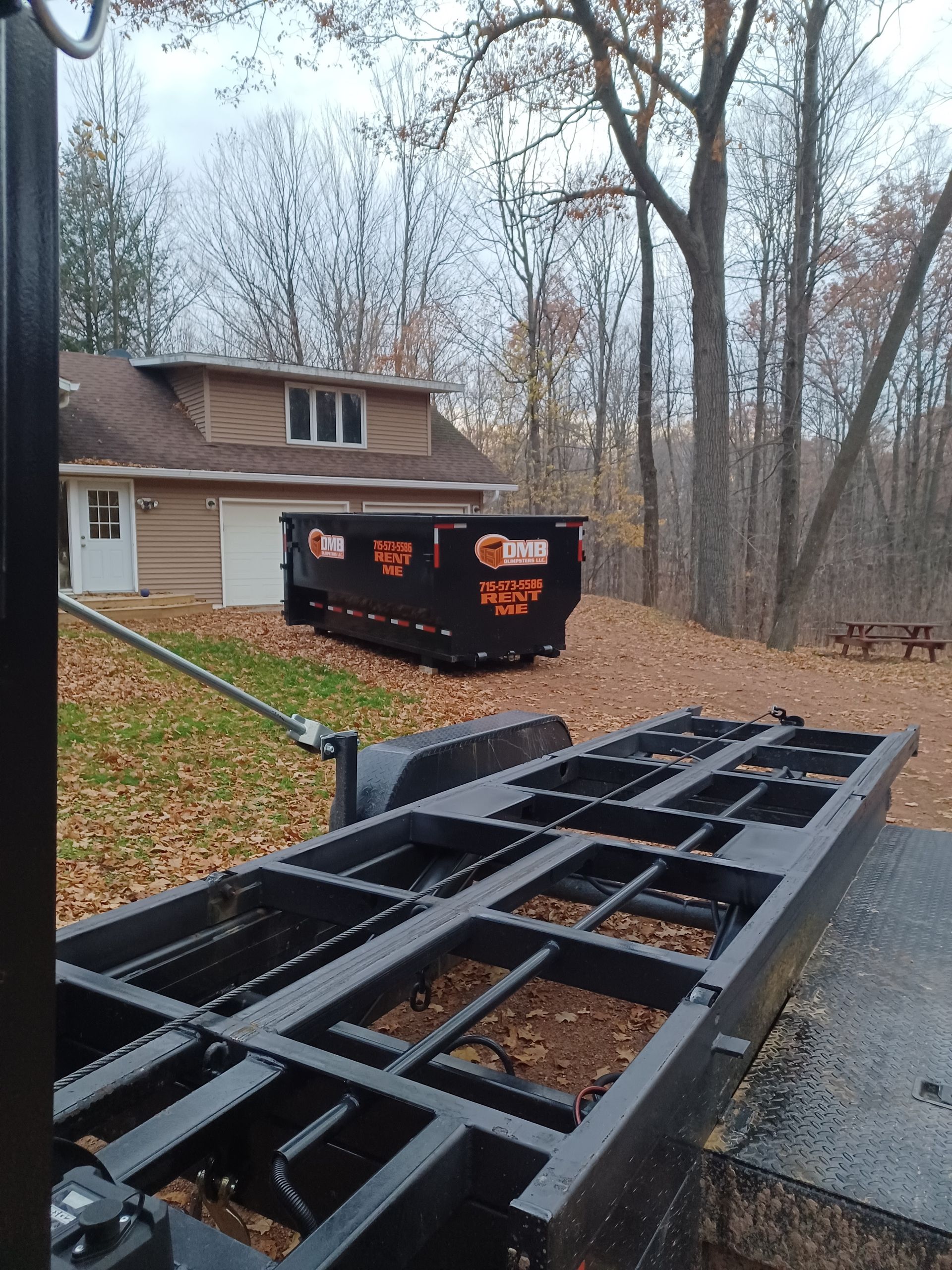 A dumpster on a trailer in front of a house