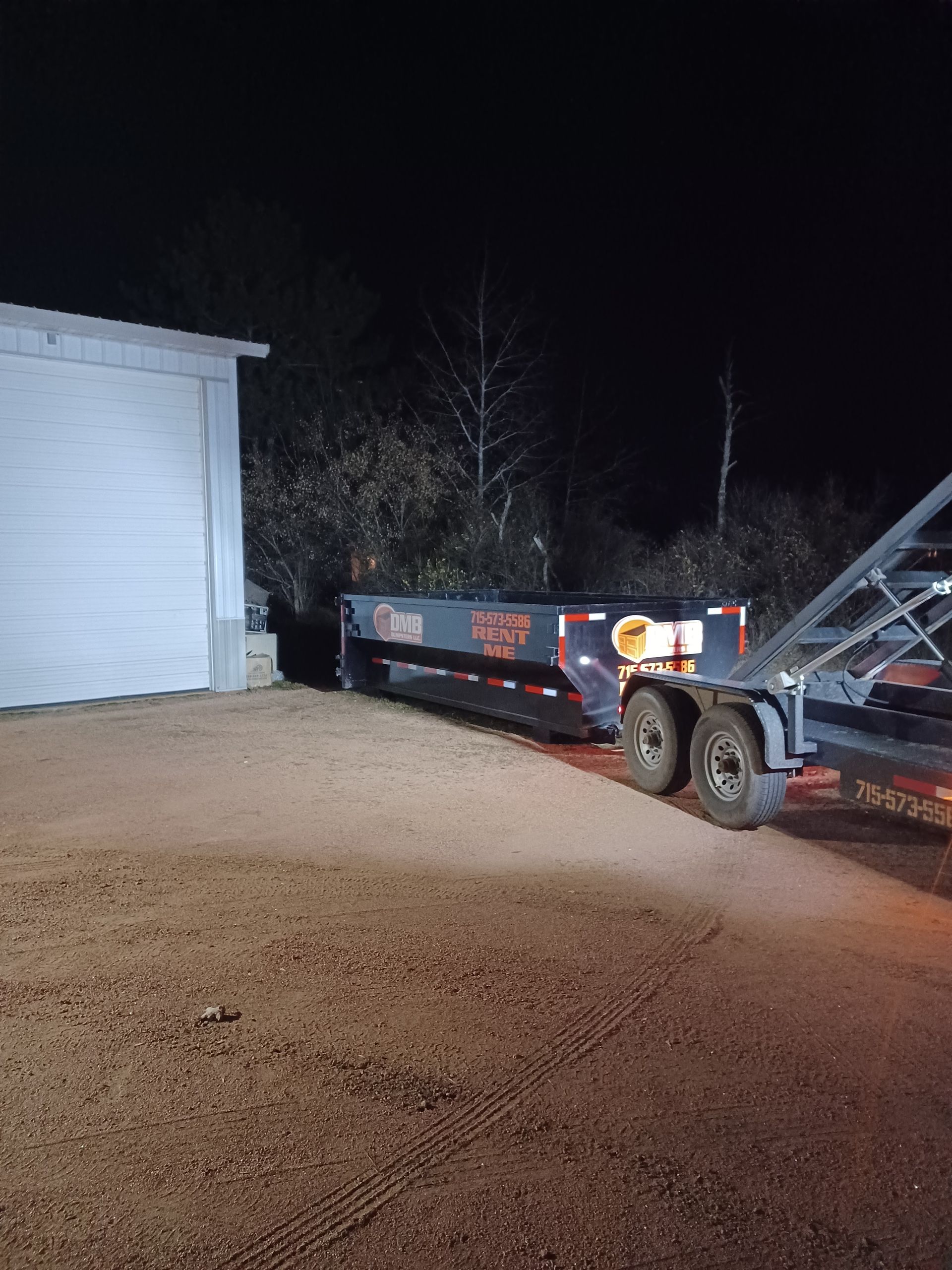 A dump truck is parked in front of a garage at night.