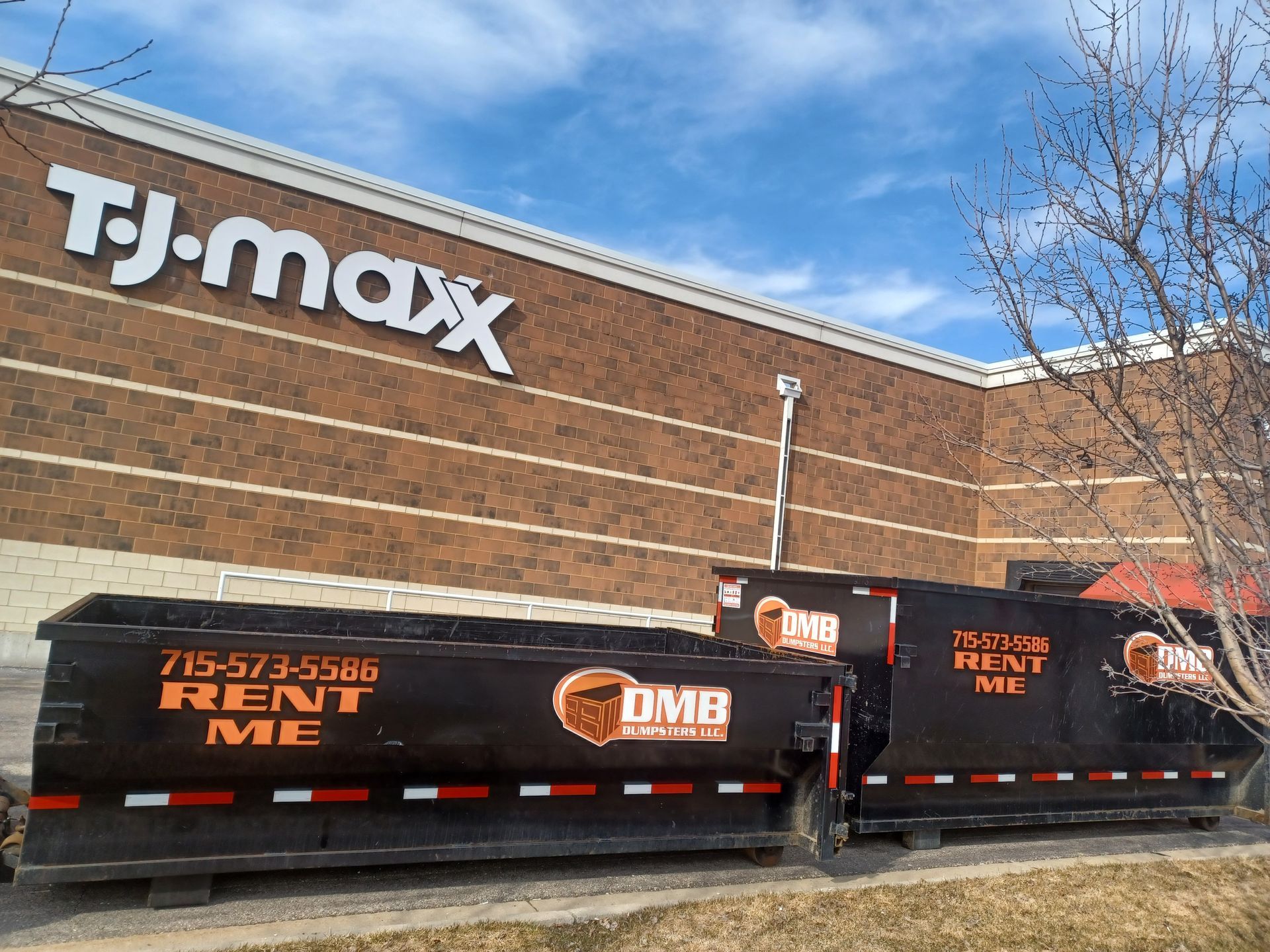 Two dumpsters are parked in front of a tj max store