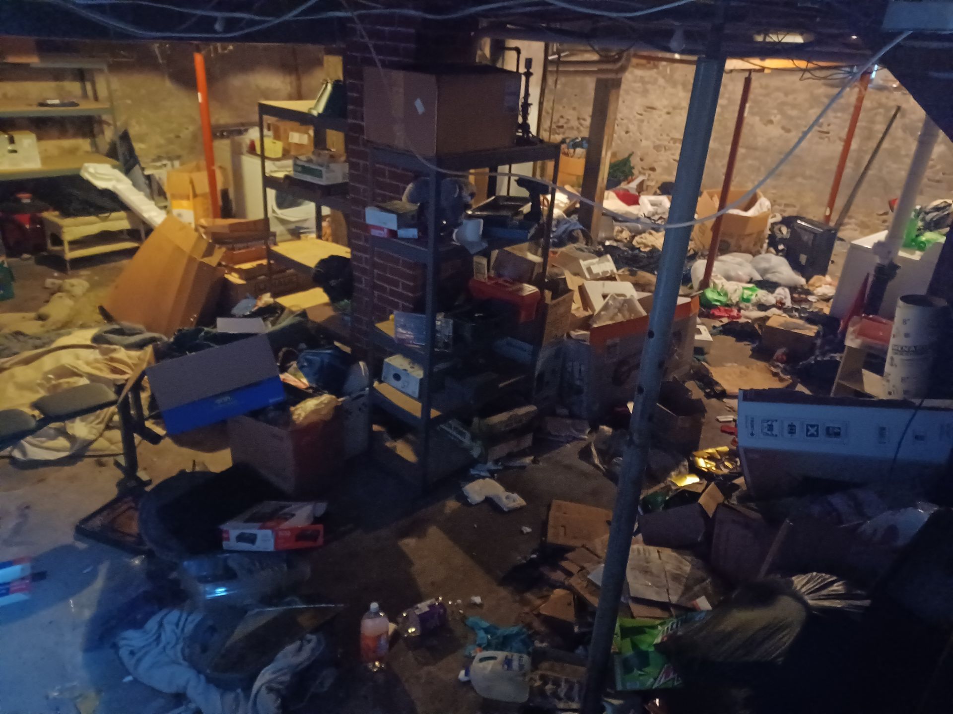 A messy basement with boxes and a sign that says ' acrylic ' on it