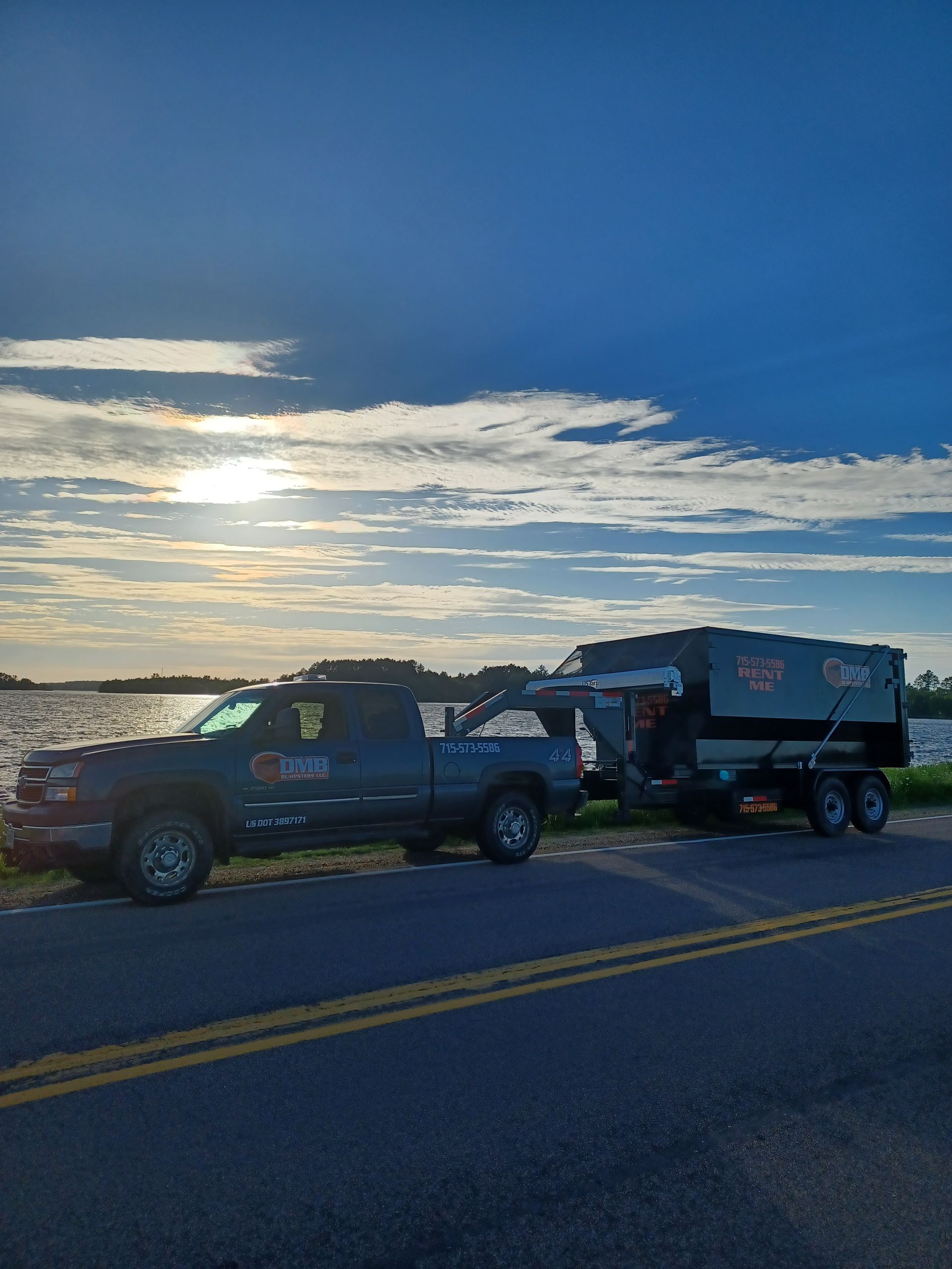 Two trucks are parked on the side of the road next to a body of water.