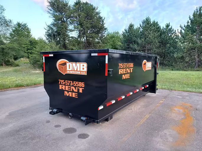 A black dumpster is parked on the side of the road.