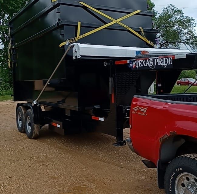 A red truck is towing a black trailer that says texas pride
